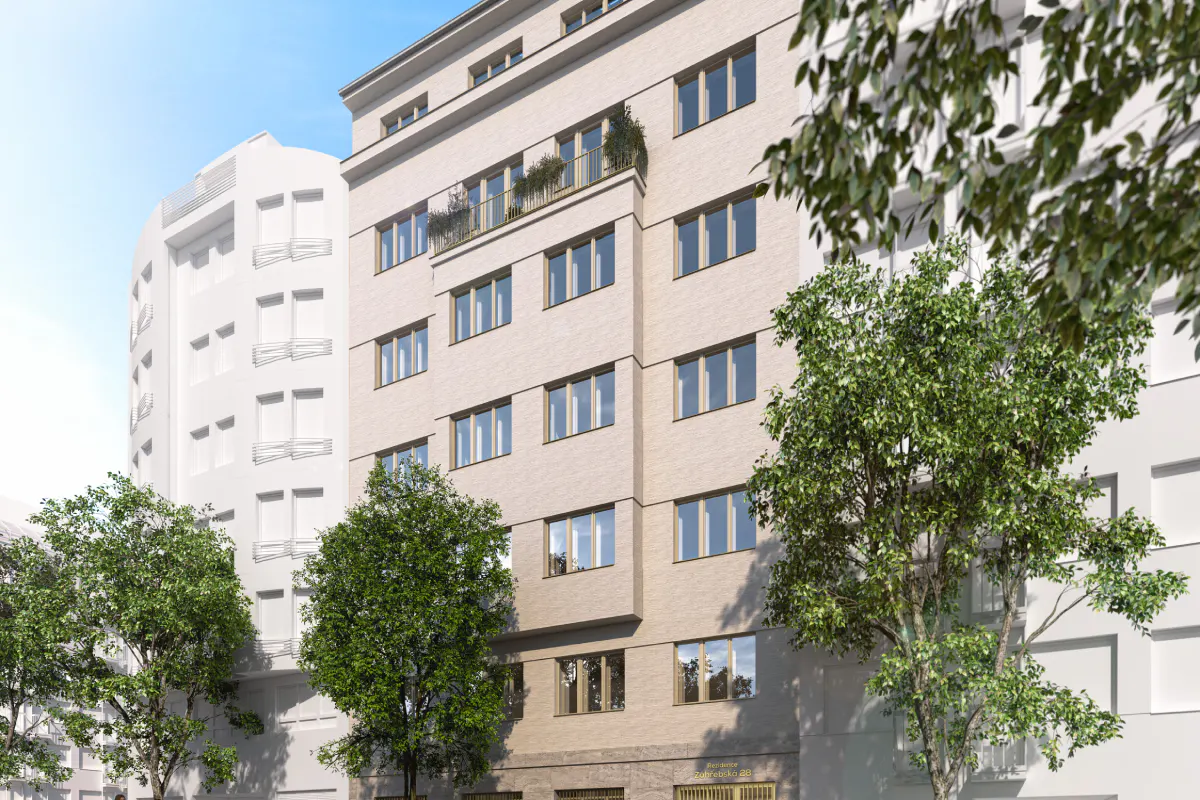 Exterior view of a multi-story beige brick apartment building with many windows and a small balcony with plants. Trees are in the foreground.