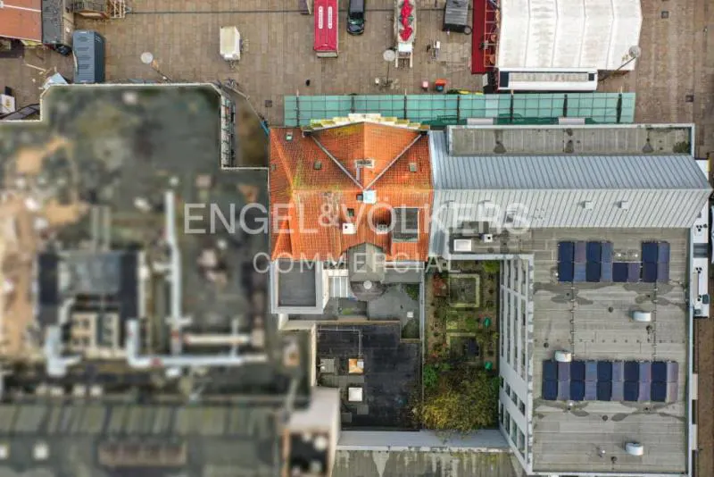 Aerial view of buildings with orange tile roofs, gray roofs, and solar panels. The Engel & Volkers Commercial logo is visible.