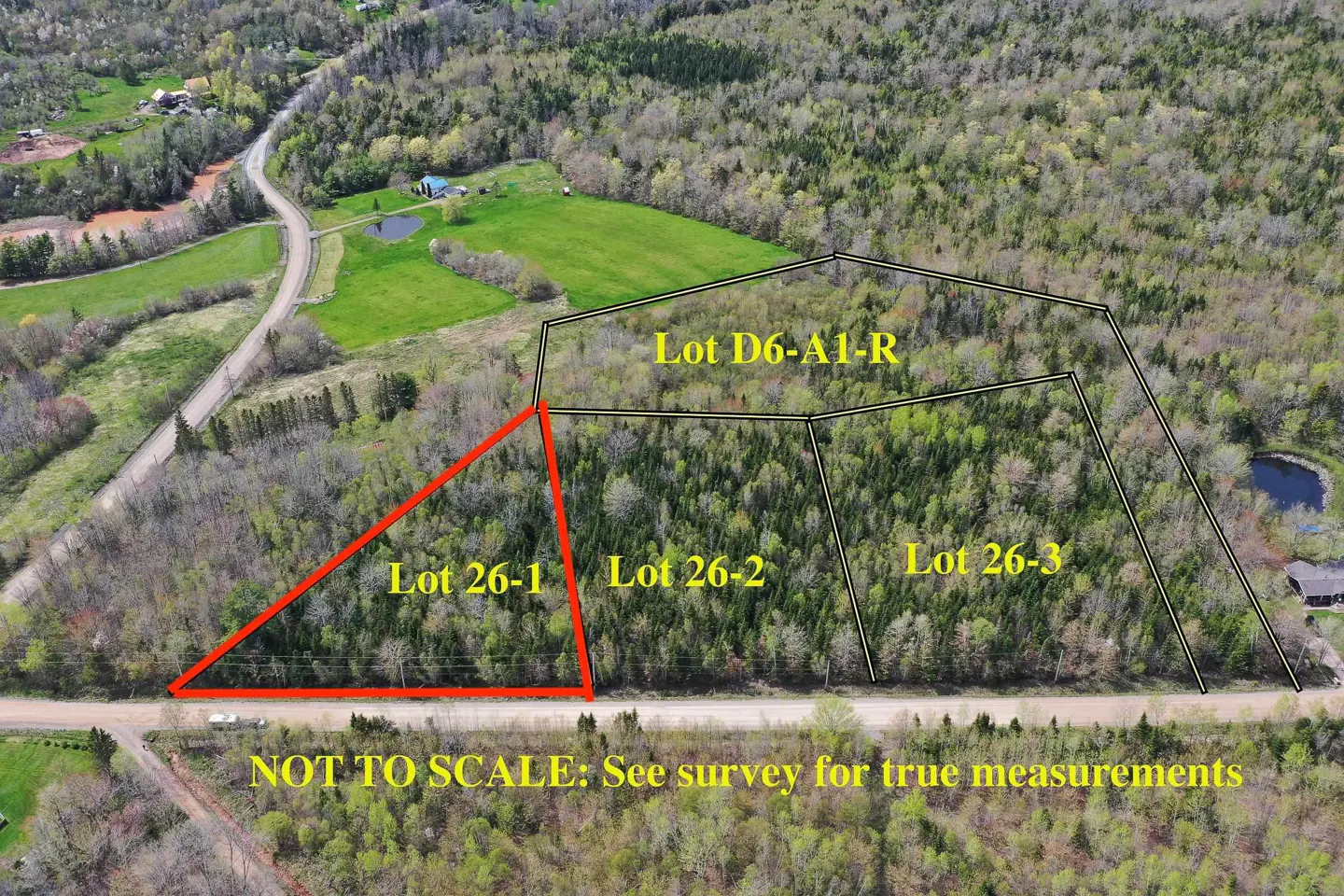 Aerial view of wooded land divided into lots, marked with black lines and red triangle. "Lot 26-1" is outlined in red. Road visible.