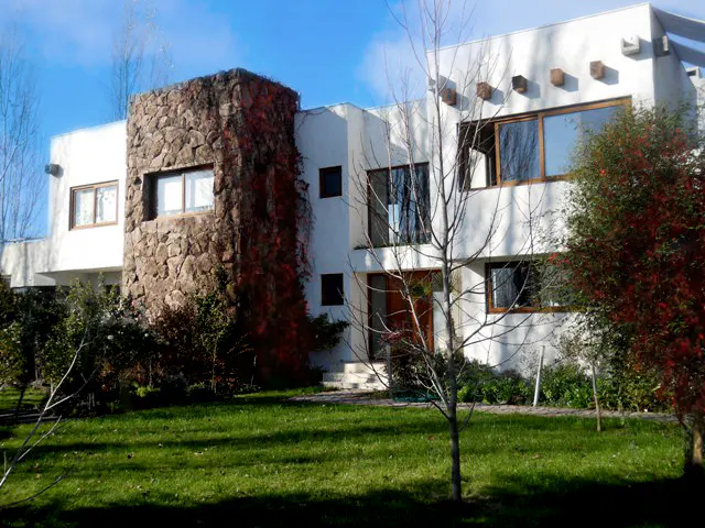 Exterior of a modern white house with a stone tower, green lawn, and blue sky.