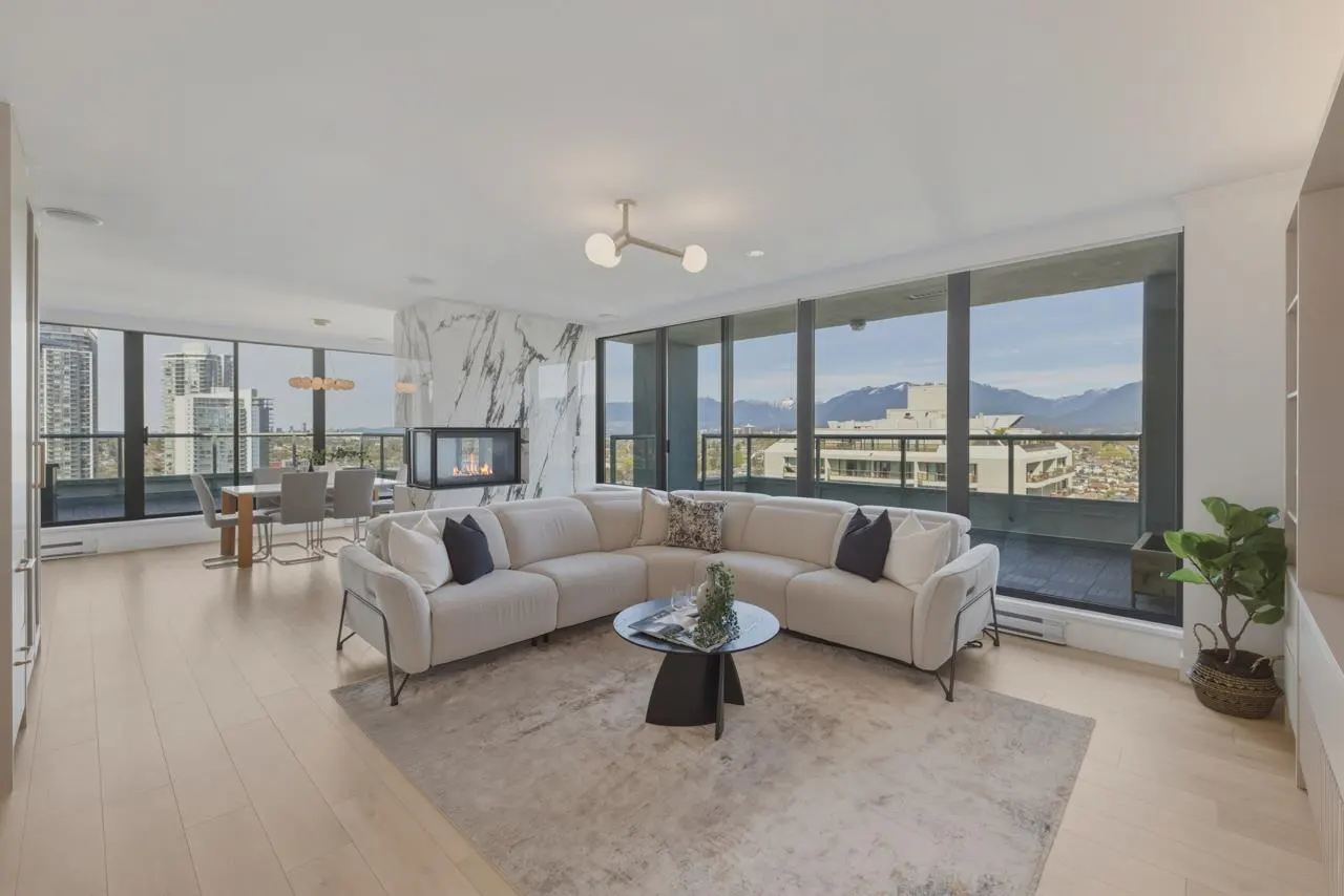 Bright, modern living room with a white sectional sofa, marble fireplace, and city views from large windows.
