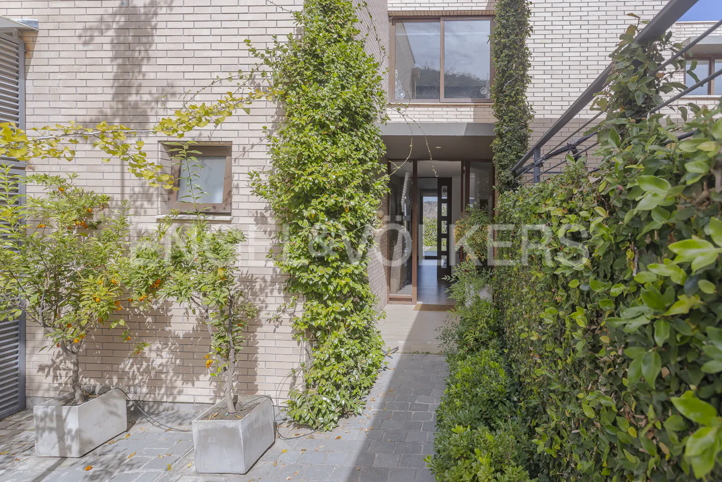 Exterior of a modern brick house with an open front door, plants, and a stone walkway.
