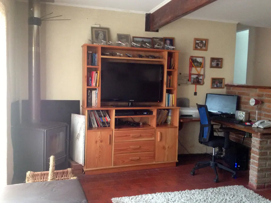 Living room with a wood-burning stove, a wooden TV stand with a TV, and a desk with a computer.