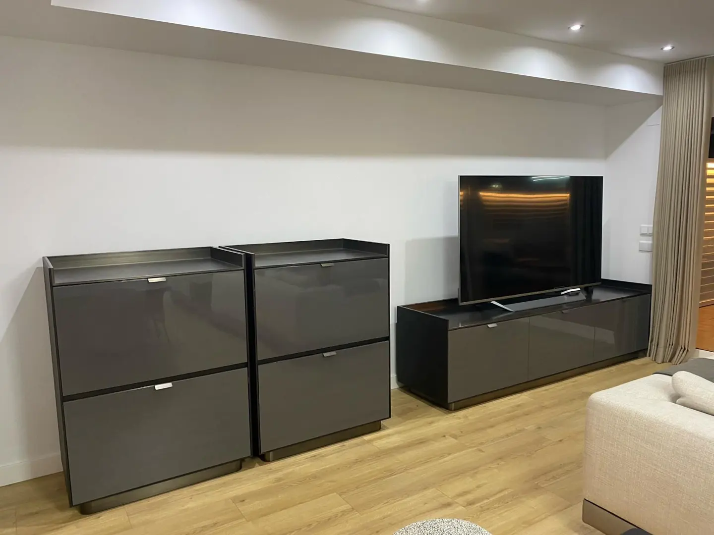 Living room with gray cabinets, a TV on a console, and light wood floors.