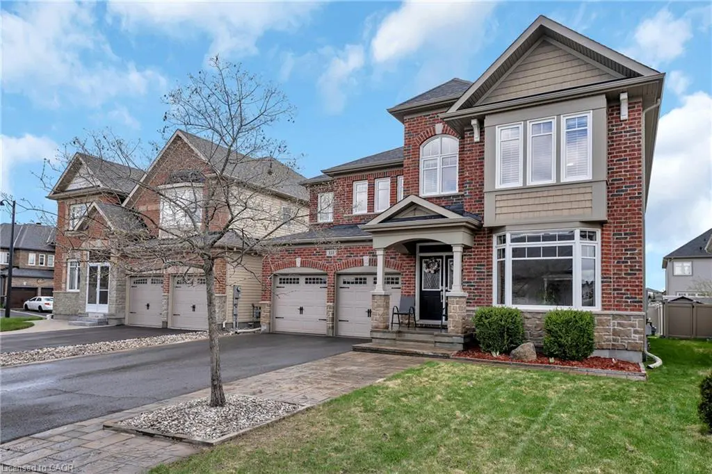 Exterior view of a two-story brick house with a lawn, driveway, and a tree in the front yard.