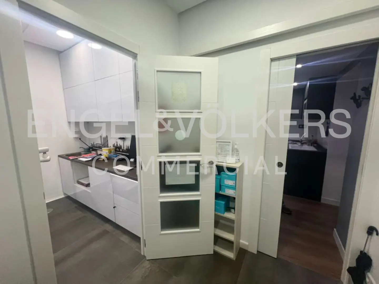Interior view of a commercial space with white cabinets, doors with frosted glass, and a small storage shelf.
