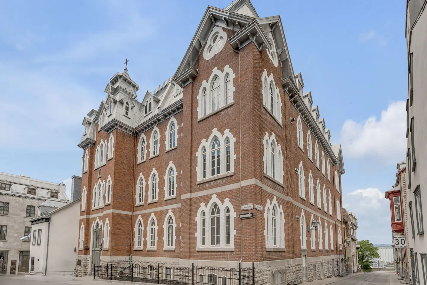Exterior view of a brick building with white trim and arched windows on a city street.