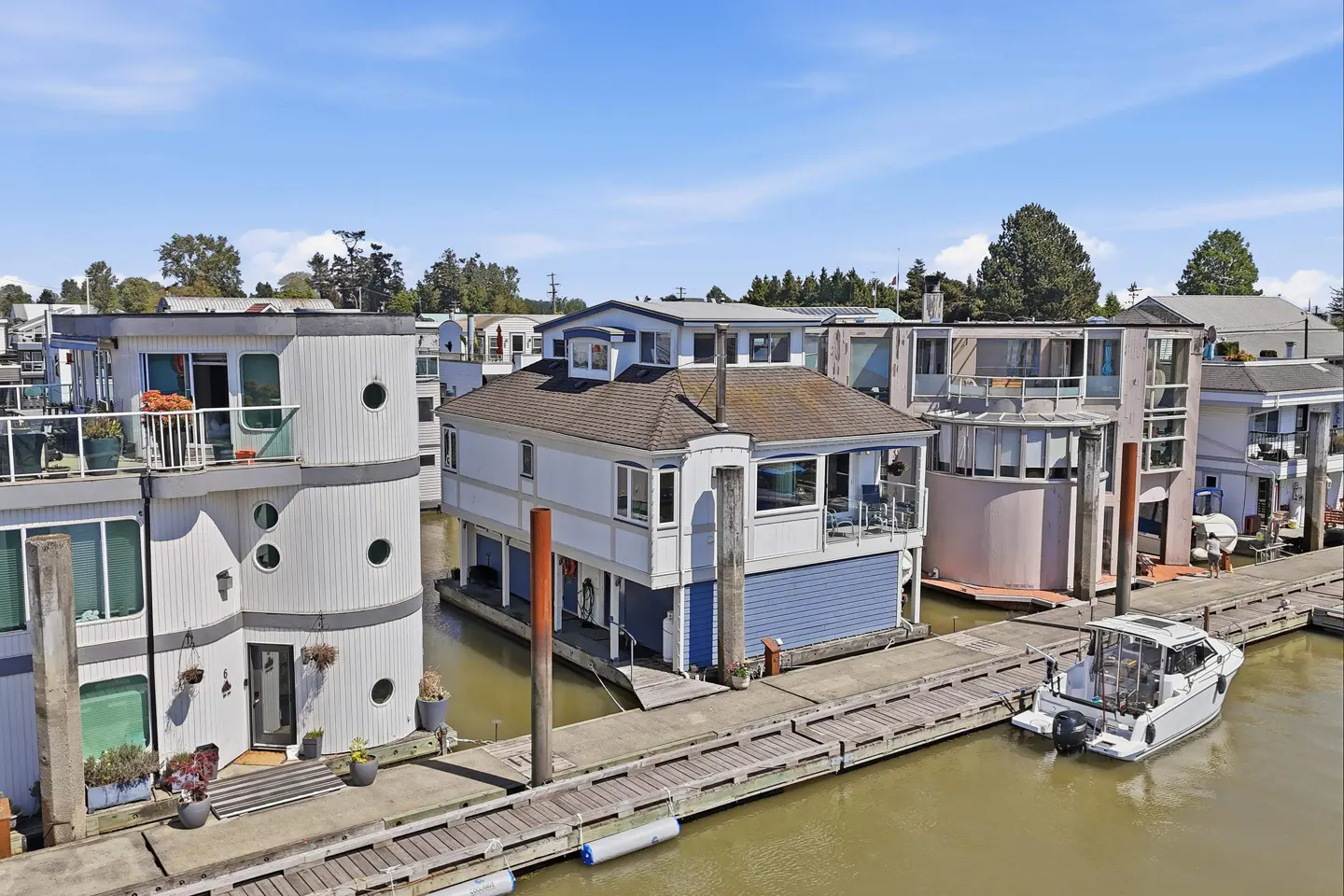 Waterfront living: Houseboats docked on a sunny day. White houseboats with decks and a boat tied to the dock.