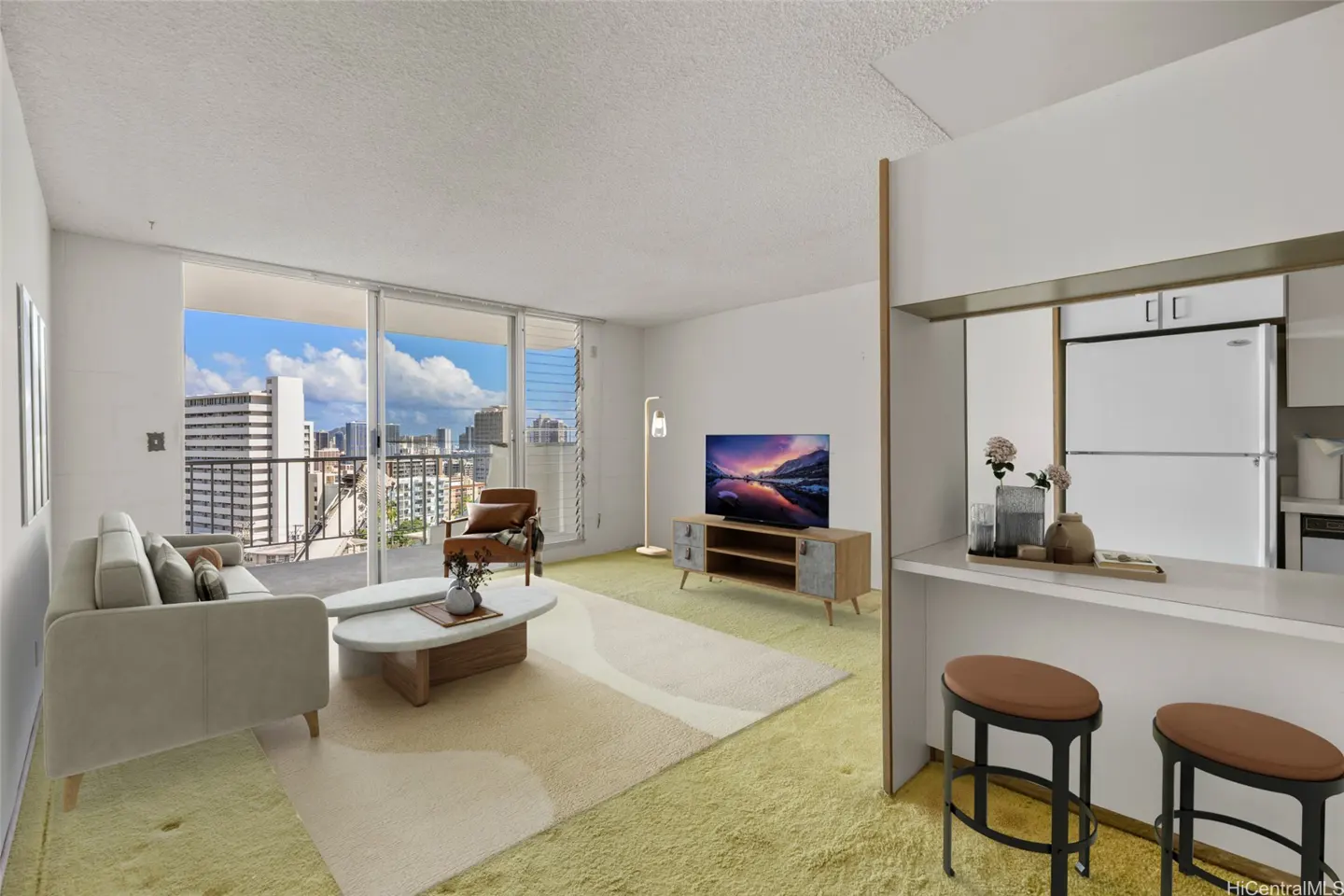 Living room with a beige sofa, brown chair, TV, and a view of the city skyline through a large window. Kitchen bar with two stools.
