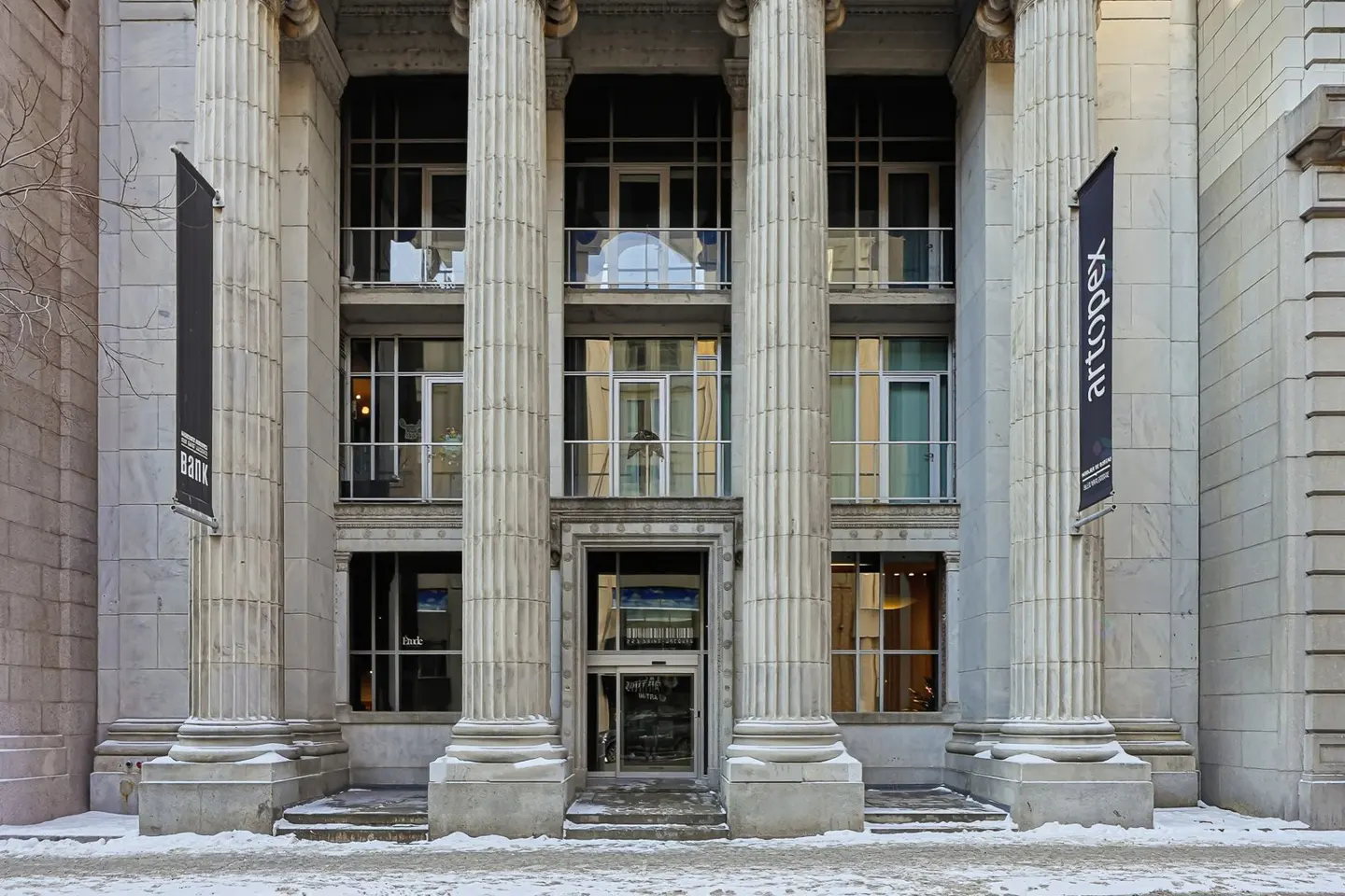 Exterior of a building with large columns and banners on either side of the entrance.