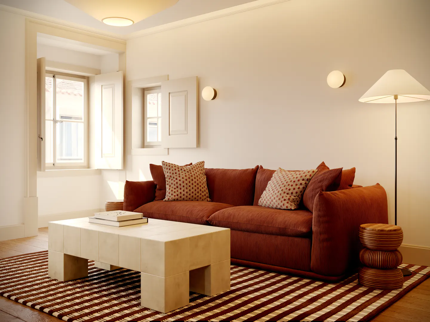 Living room with a rust-colored sofa, patterned pillows, and a light-colored coffee table on a striped rug. Windows with shutters and wall sconces add light.