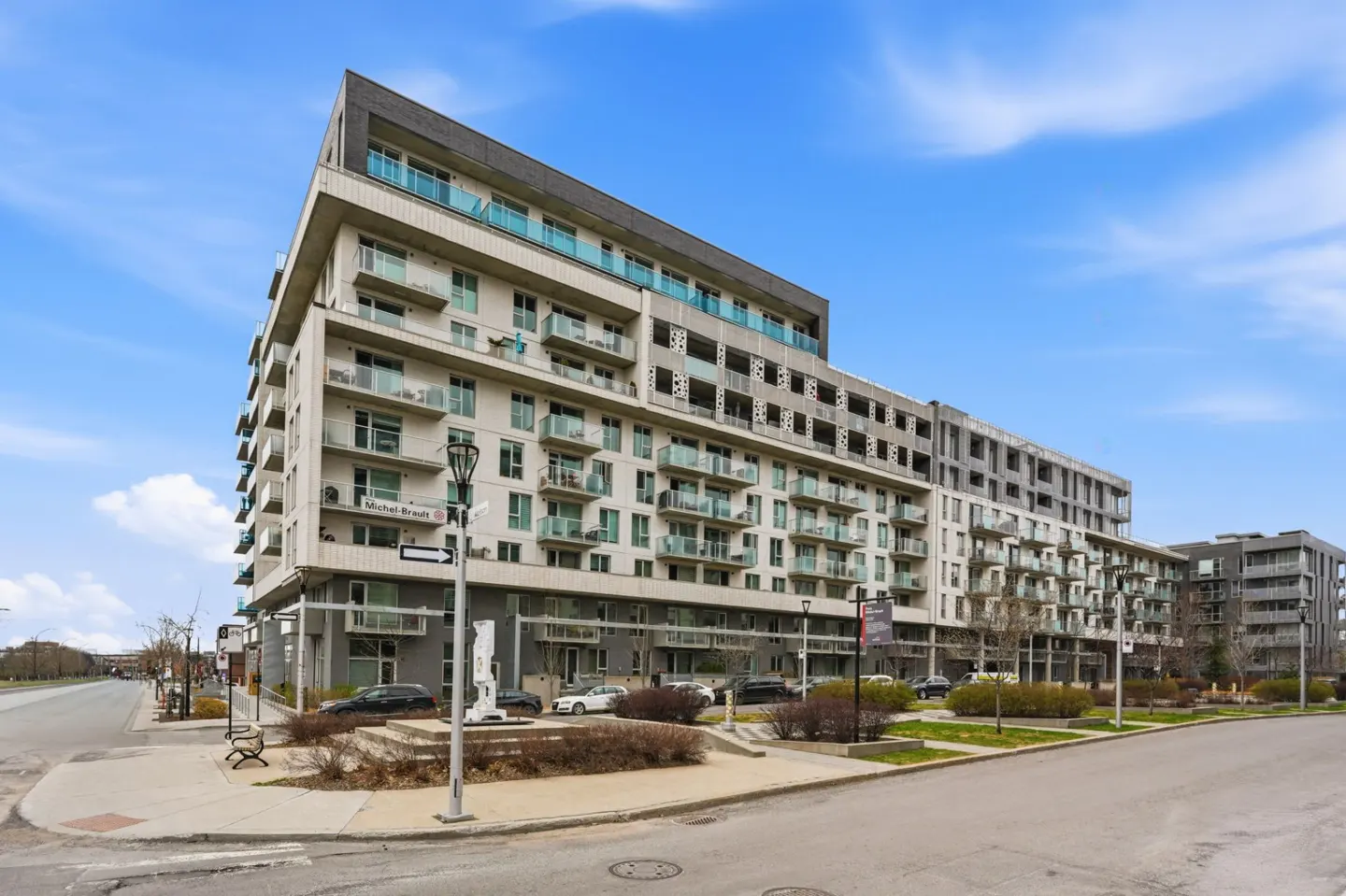 Exterior view of a modern, multi-story apartment building with balconies and a blue sky background.