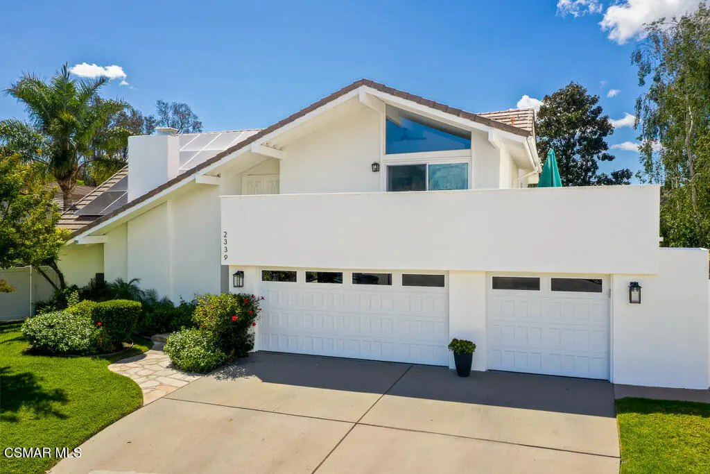 Exterior of a two-story white house with a two-car garage, green lawn, and blue sky.