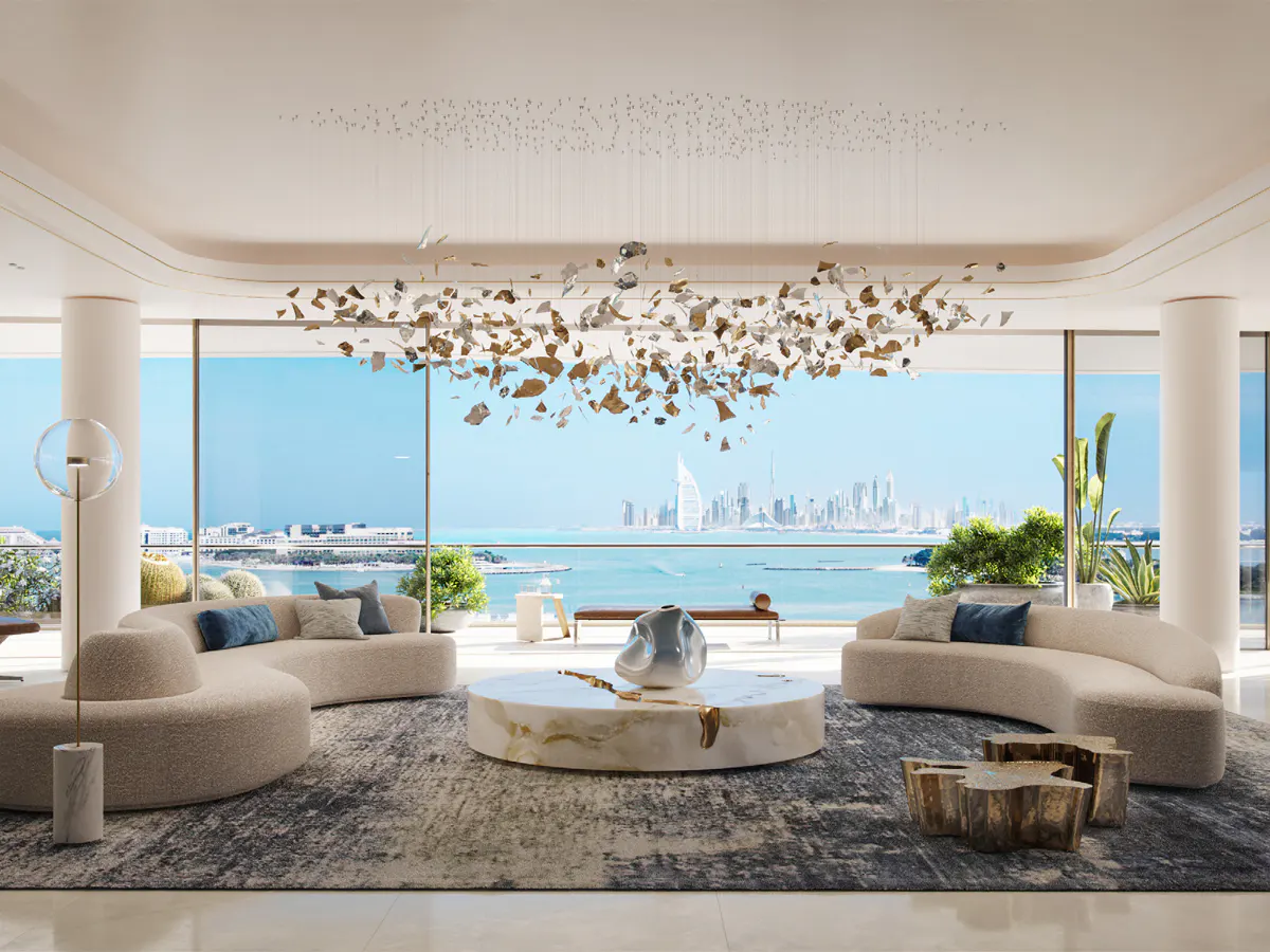 A bright living room with curved sofas, a marble table, and a large window overlooking the ocean and city skyline.