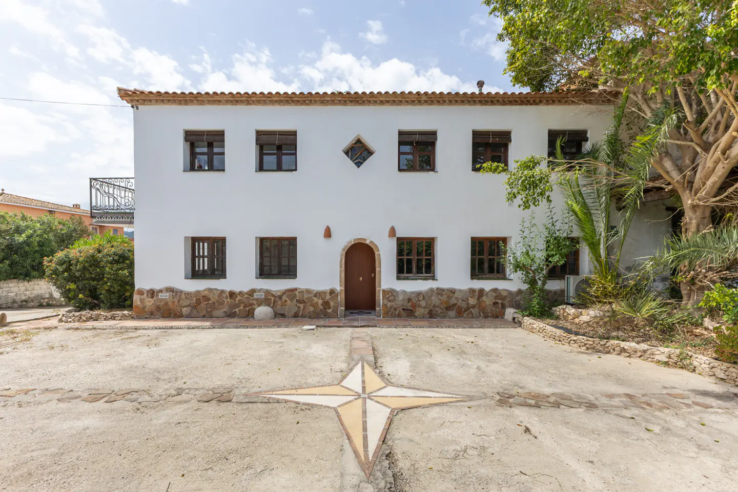 Two-story white house with brown trim and a brown door. A star design is on the driveway.