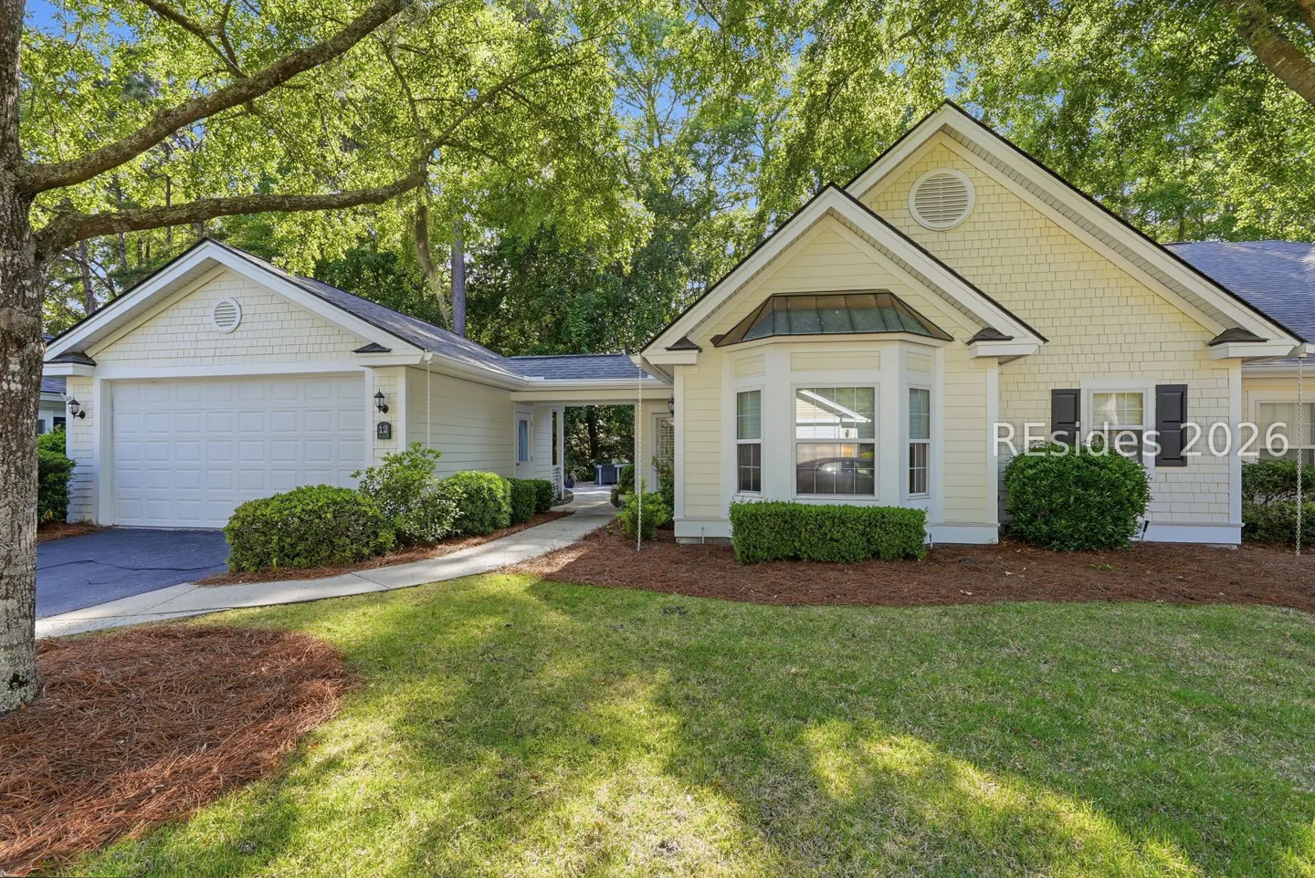 A one-story, light yellow house with a garage and a green lawn.