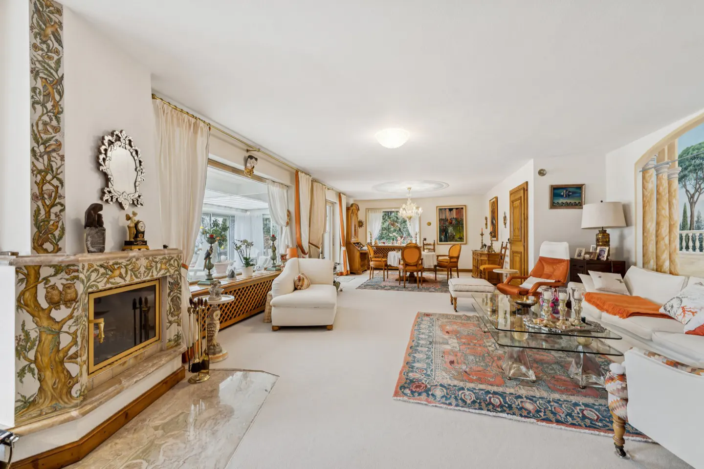 A bright, spacious living room with white walls, a decorative fireplace, and a dining area in the background.