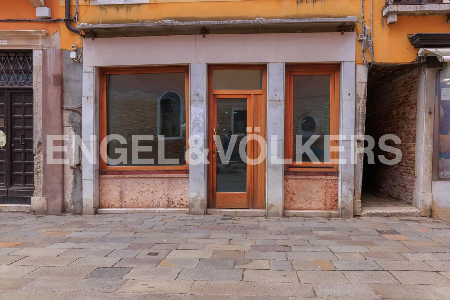 Exterior of a commercial building with a wooden door and windows, stone facade, and the Engel & Völkers logo.