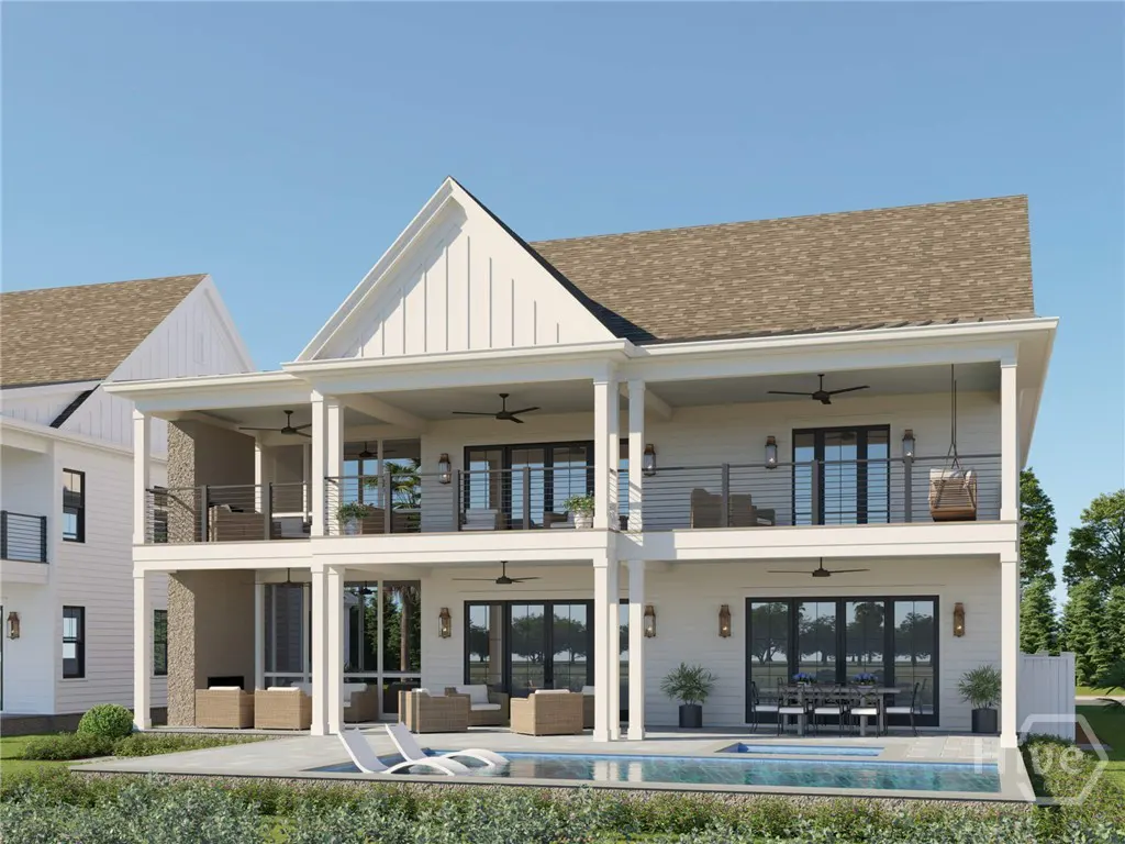 Two-story white modern farmhouse with a covered patio, balcony, swimming pool, and outdoor dining area under a clear sky.