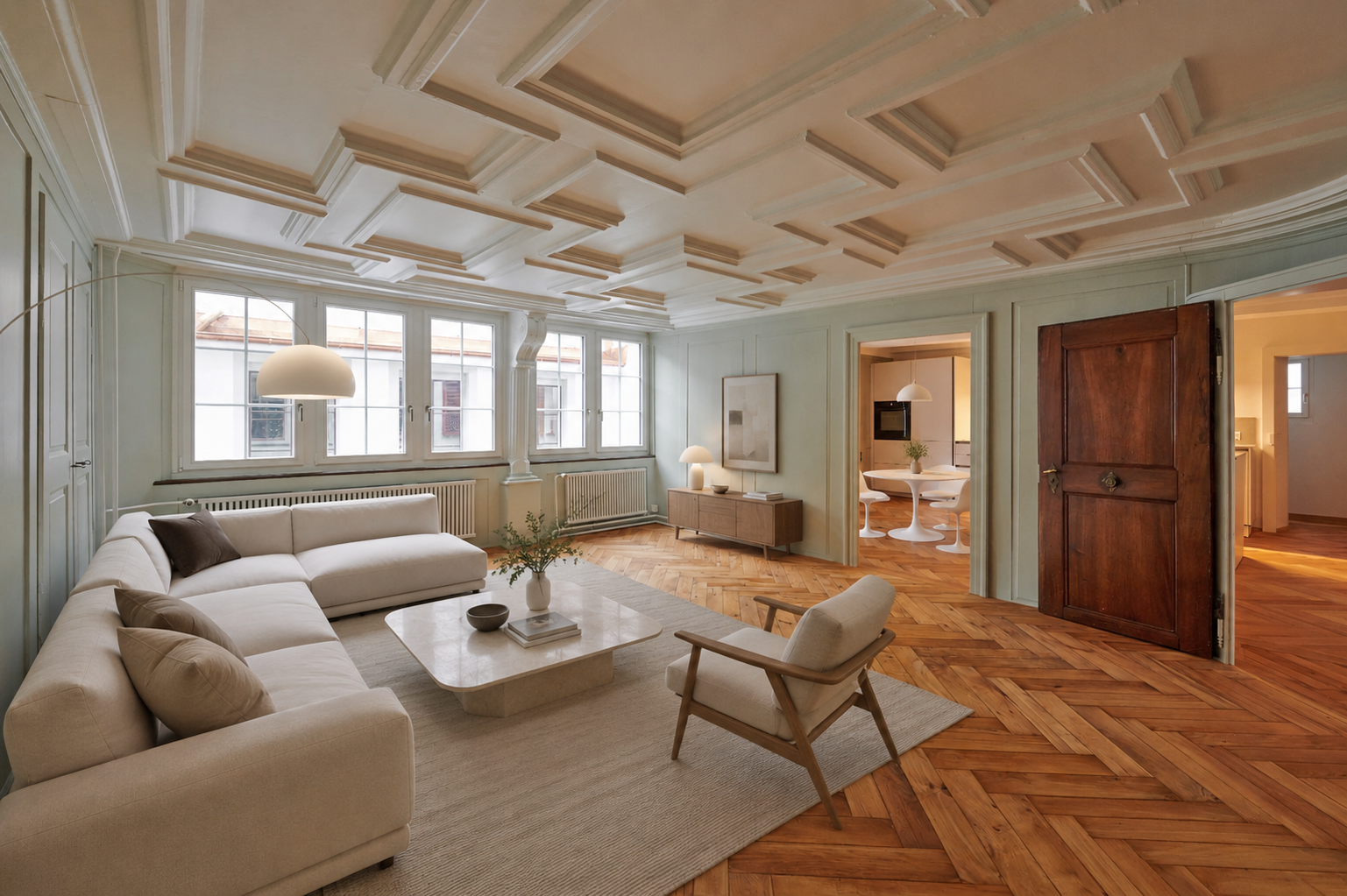 Living room with white sectional sofa, armchair, and coffee table on herringbone wood floors under a coffered ceiling.