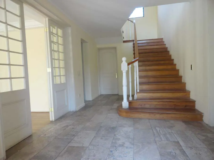 Foyer with tile floor, white walls, and a wooden staircase with white banister. Glass paneled doors lead to another room.