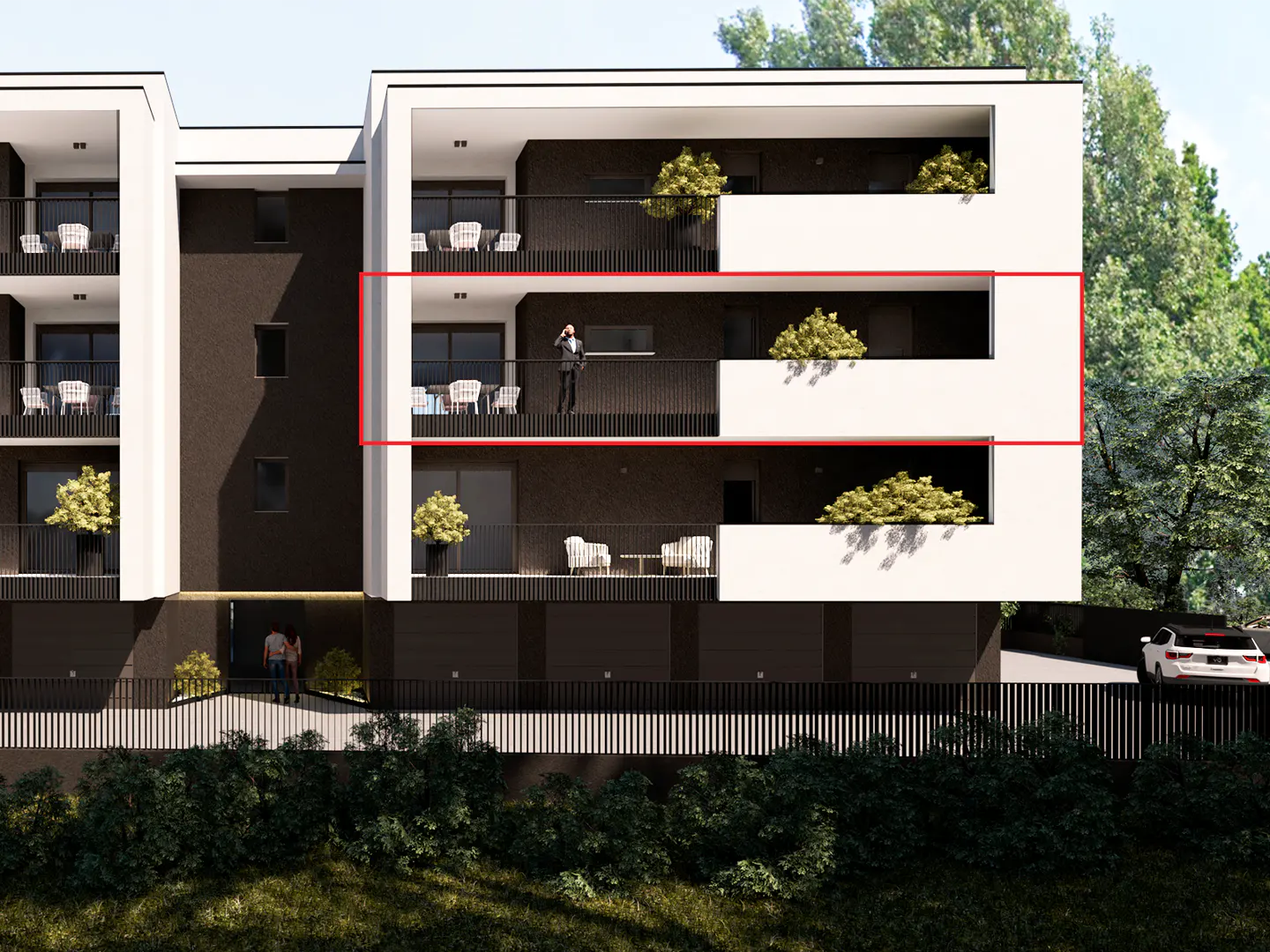 Modern apartment building with black and white facade. A man stands on a balcony, talking on his phone. Trees in the background.