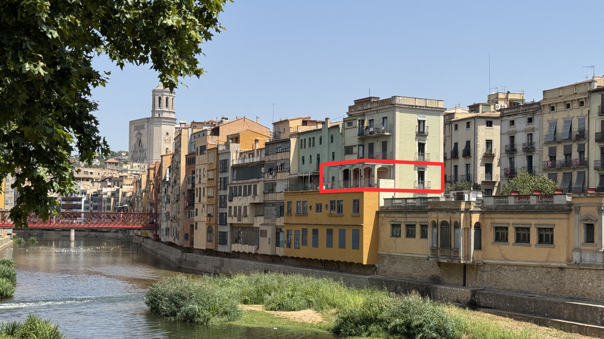A red box highlights a terrace on a light-colored building overlooking a river in a historic European city.