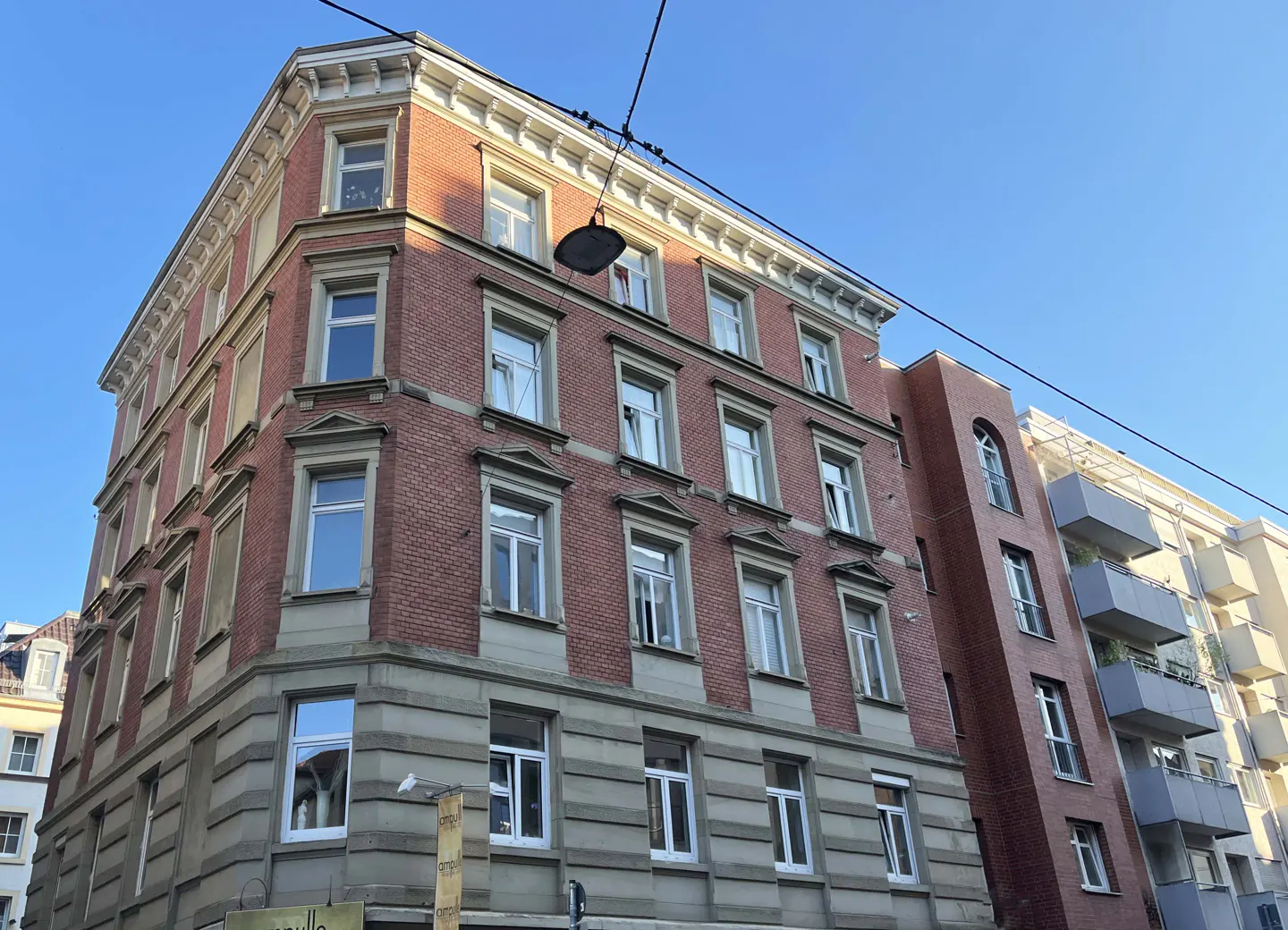 A low-angle shot of a red brick building with white-framed windows under a clear blue sky.