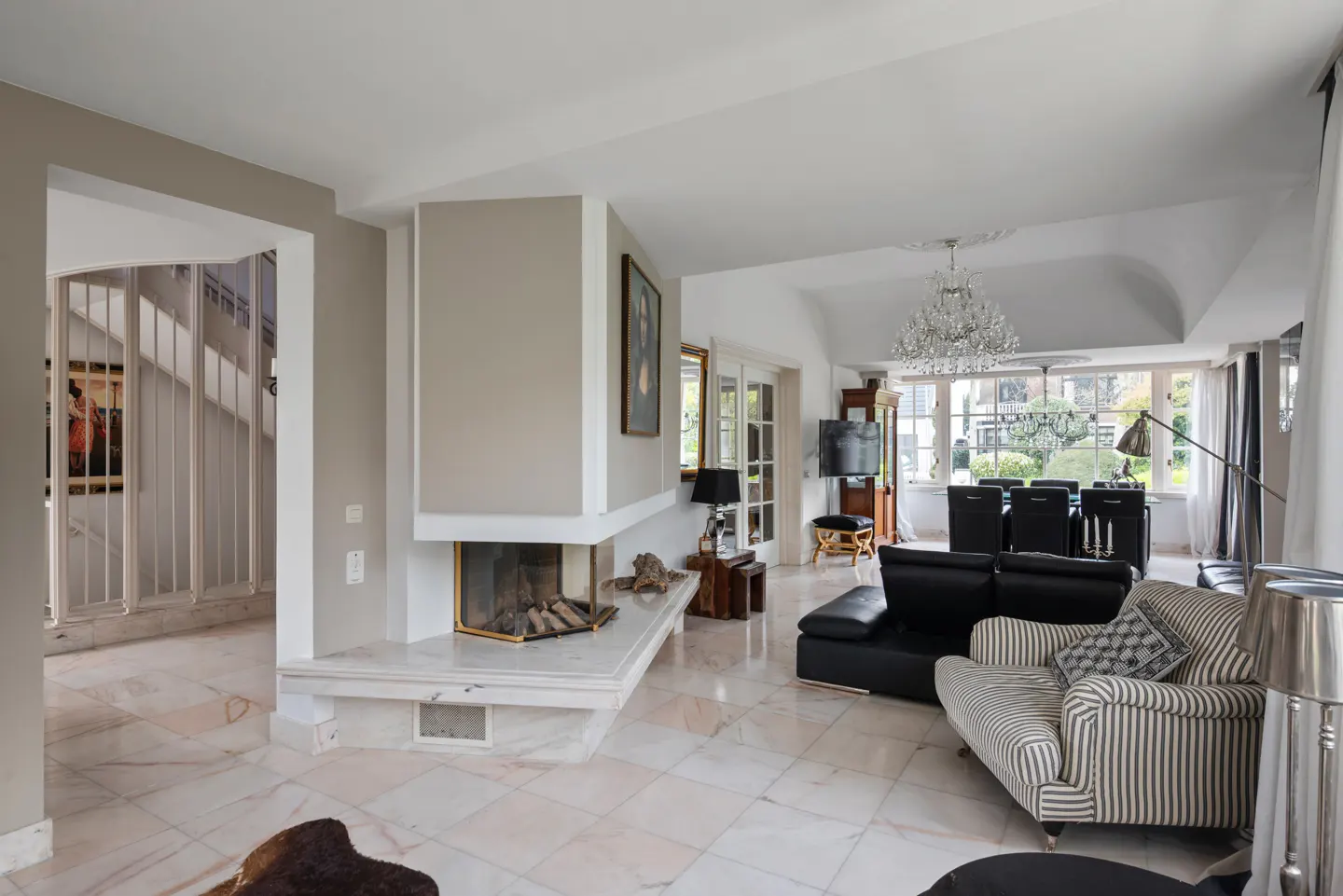 A bright living room with a marble floor, a fireplace, and a view of the dining area.