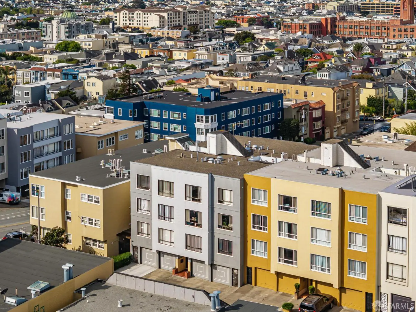 An aerial view of a dense urban neighborhood with colorful buildings and a cityscape background.