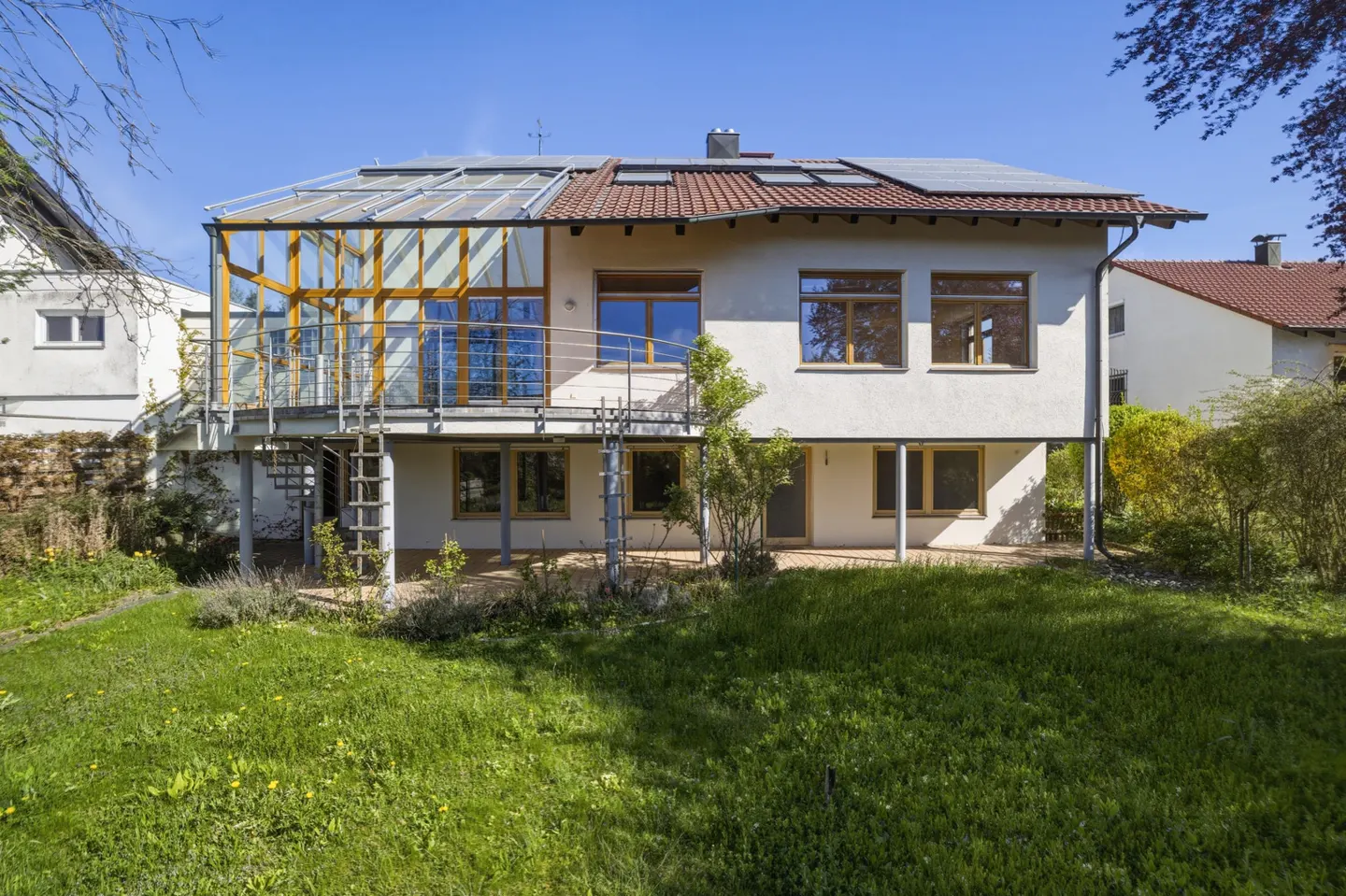 Two-story white house with a glass sunroom addition, a spiral staircase, and a green lawn.