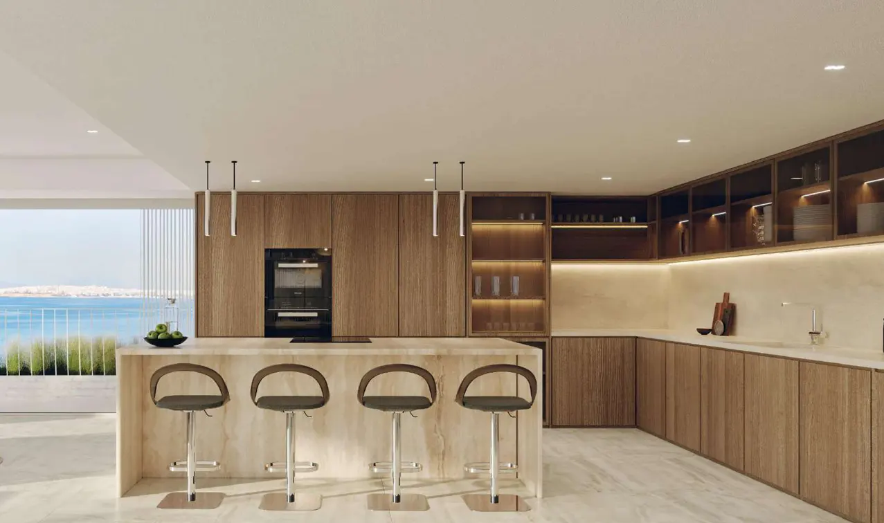 A modern kitchen with wood cabinets, a marble island with three stools, and a view of the ocean.