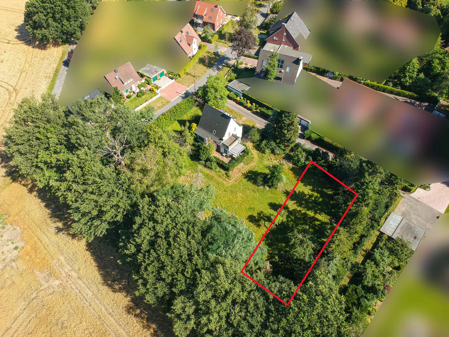 Aerial view of a vacant lot outlined in red, surrounded by trees and houses in a rural setting.