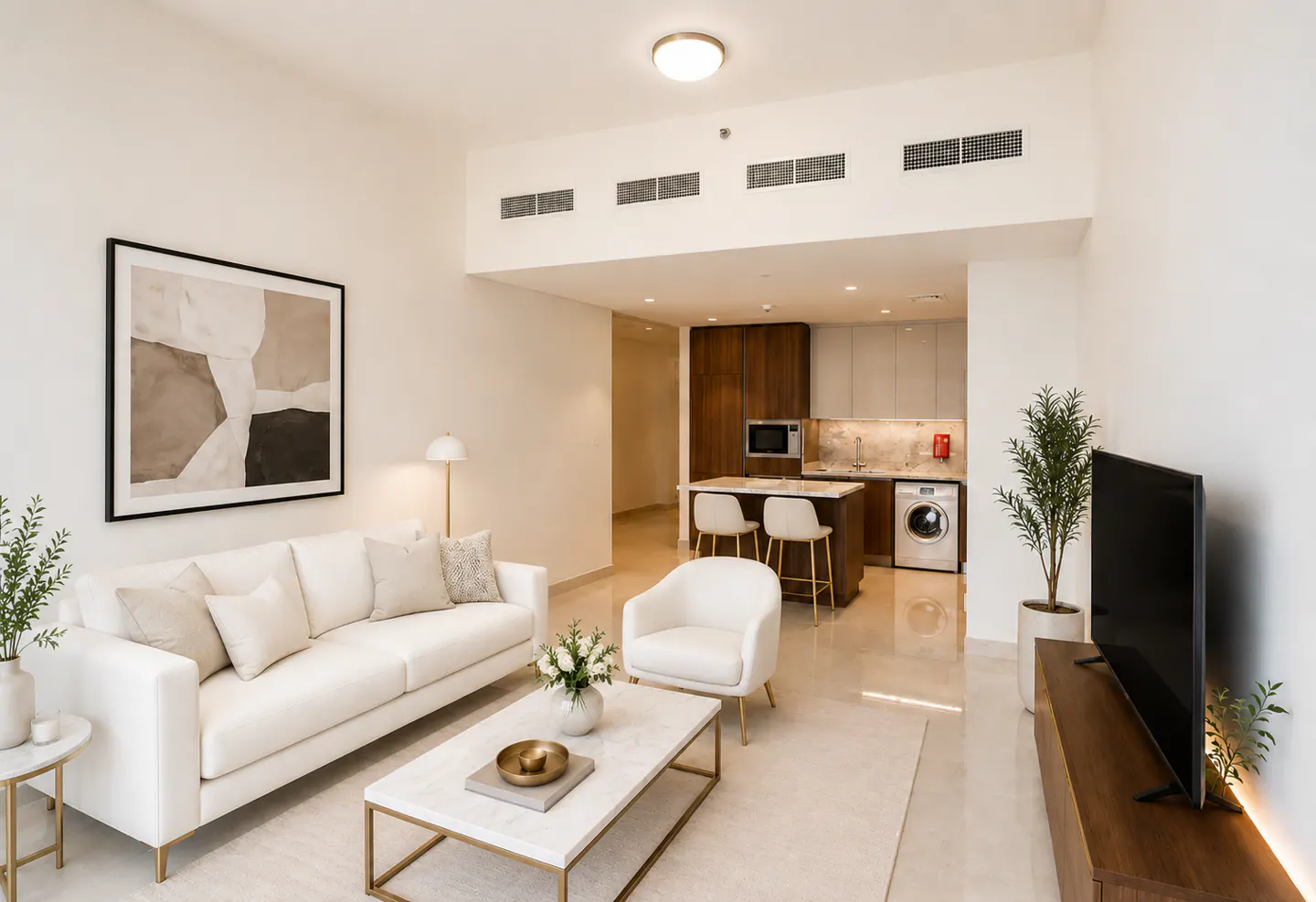 Bright, modern apartment interior with white sofa, chair, and marble coffee table. Open kitchen with island, stools, and stainless steel appliances.