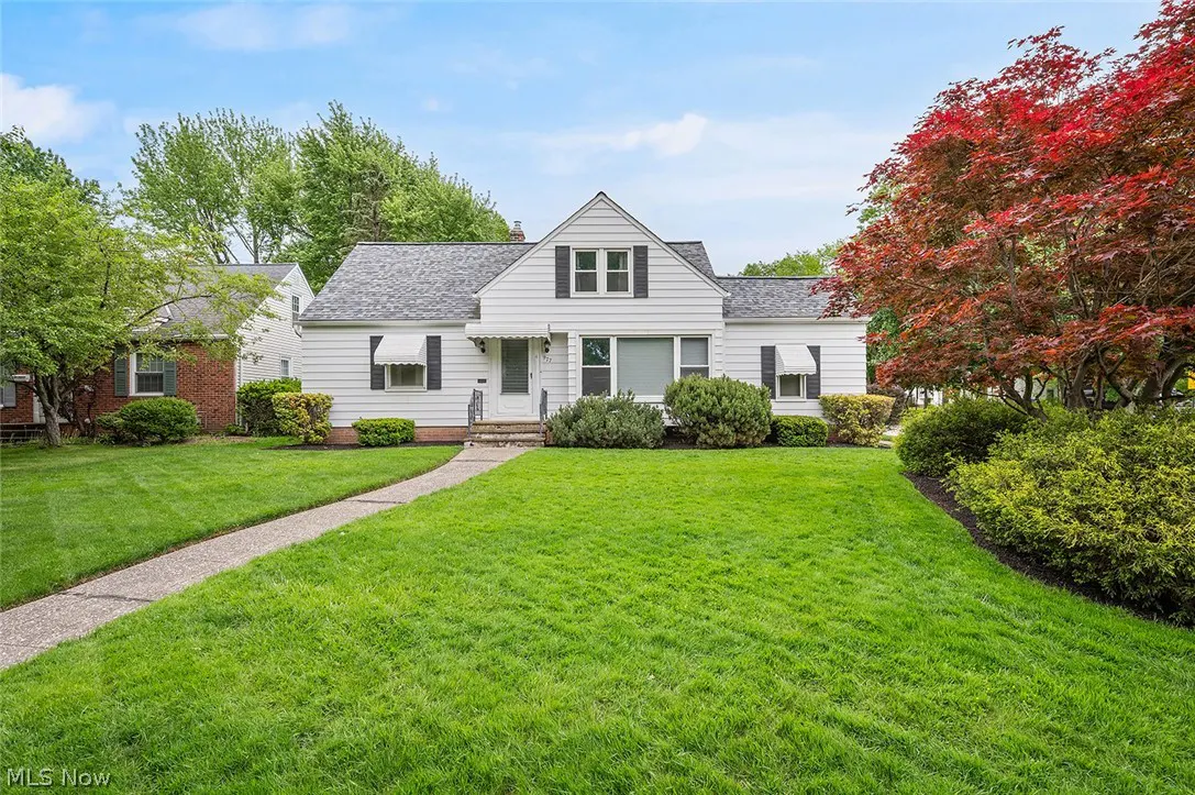 A white, one-story house with a gray roof, black shutters, and a green lawn.