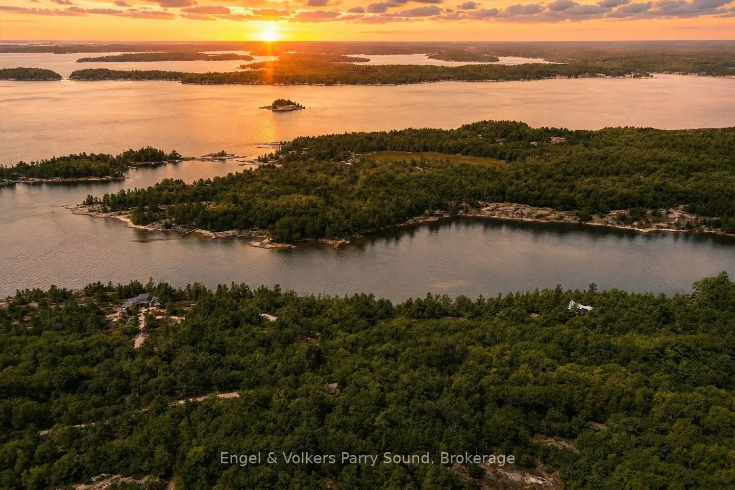 Aerial view of islands and lake at sunset. Green trees cover the islands, and the sun reflects on the water.