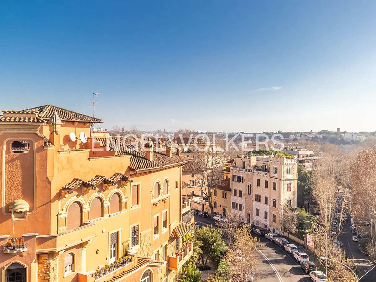 View of orange buildings and a tree-lined street under a blue sky in Rome, Italy.
