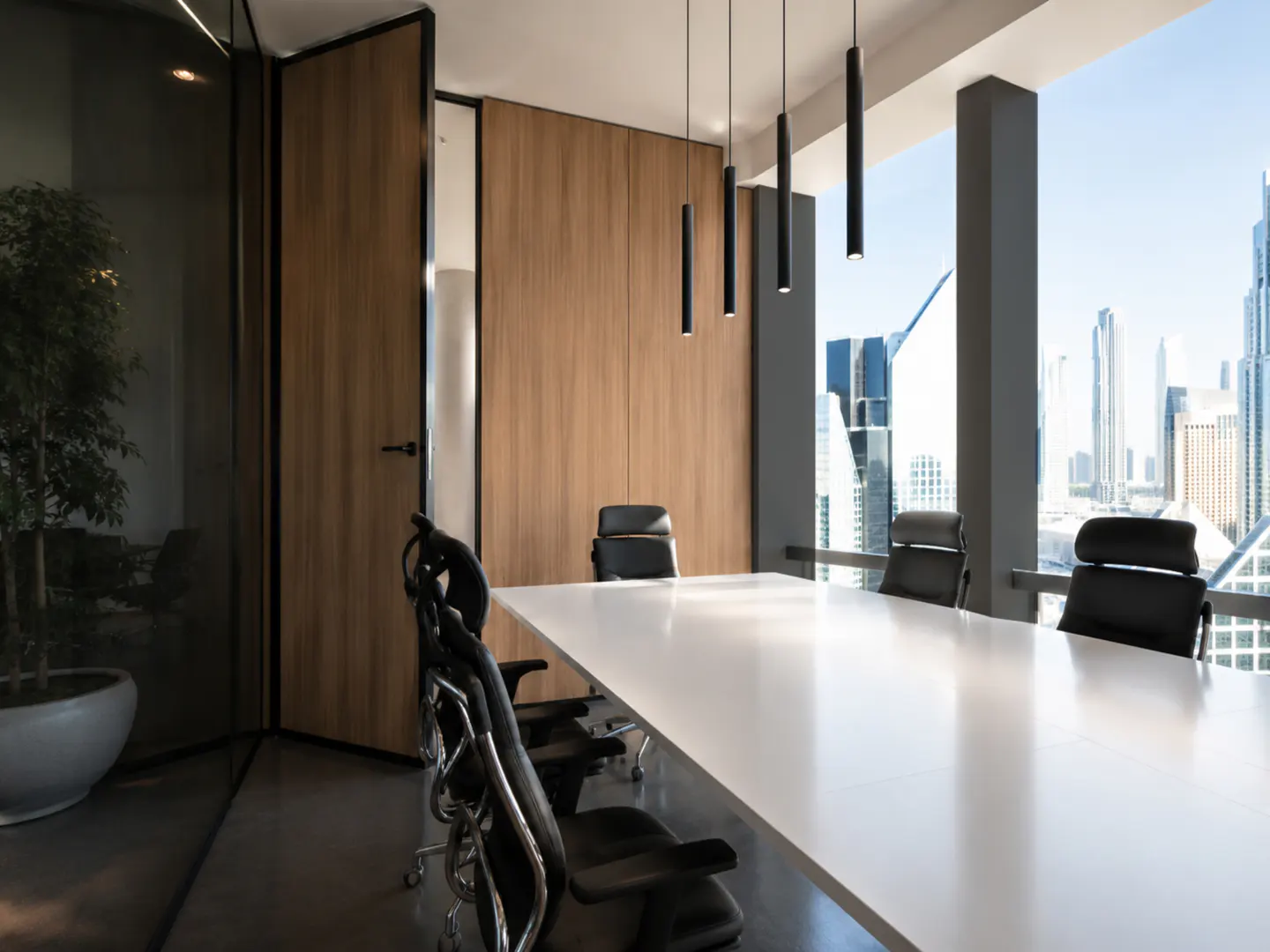 Modern office boardroom with a white table, black chairs, wood-paneled walls, and a city skyline view through windows.