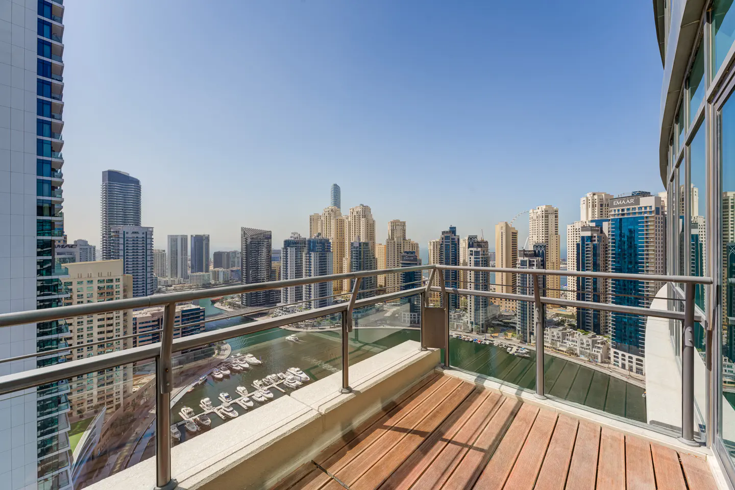 View from a wooden balcony overlooking a marina and city skyline under a clear blue sky.