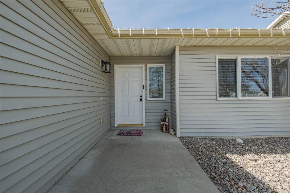 Exterior view of a house with gray siding, a white front door, and a concrete walkway.
