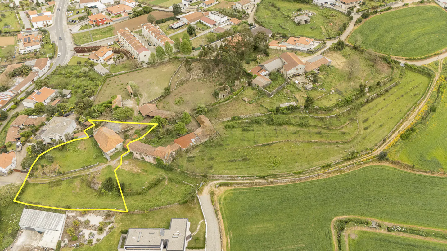 Aerial view of a property with a yellow outline, featuring old stone buildings with red tile roofs, surrounded by green grass and trees.