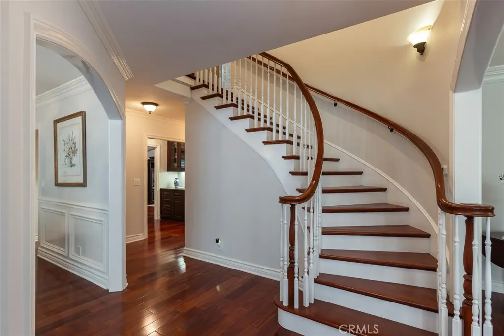 Elegant curved staircase with dark wood treads and white railings in a bright foyer with hardwood floors.