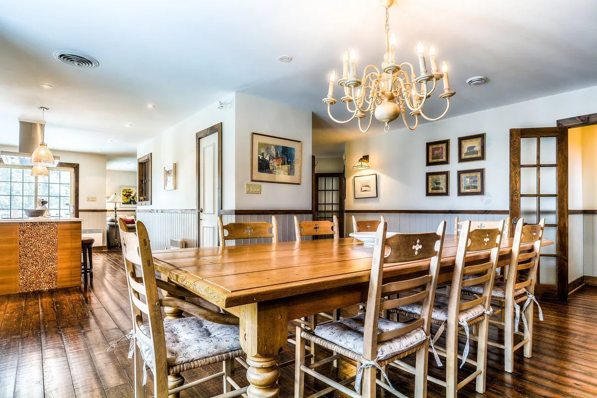 A dining room with a long wooden table, chairs with floral cushions, and a chandelier.