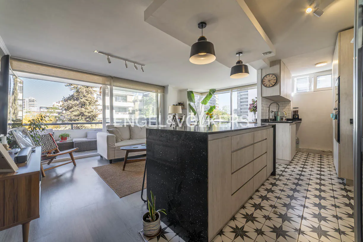 Open-concept living space with a kitchen island, sofa, and balcony with city views. The floor is patterned with black and white stars.