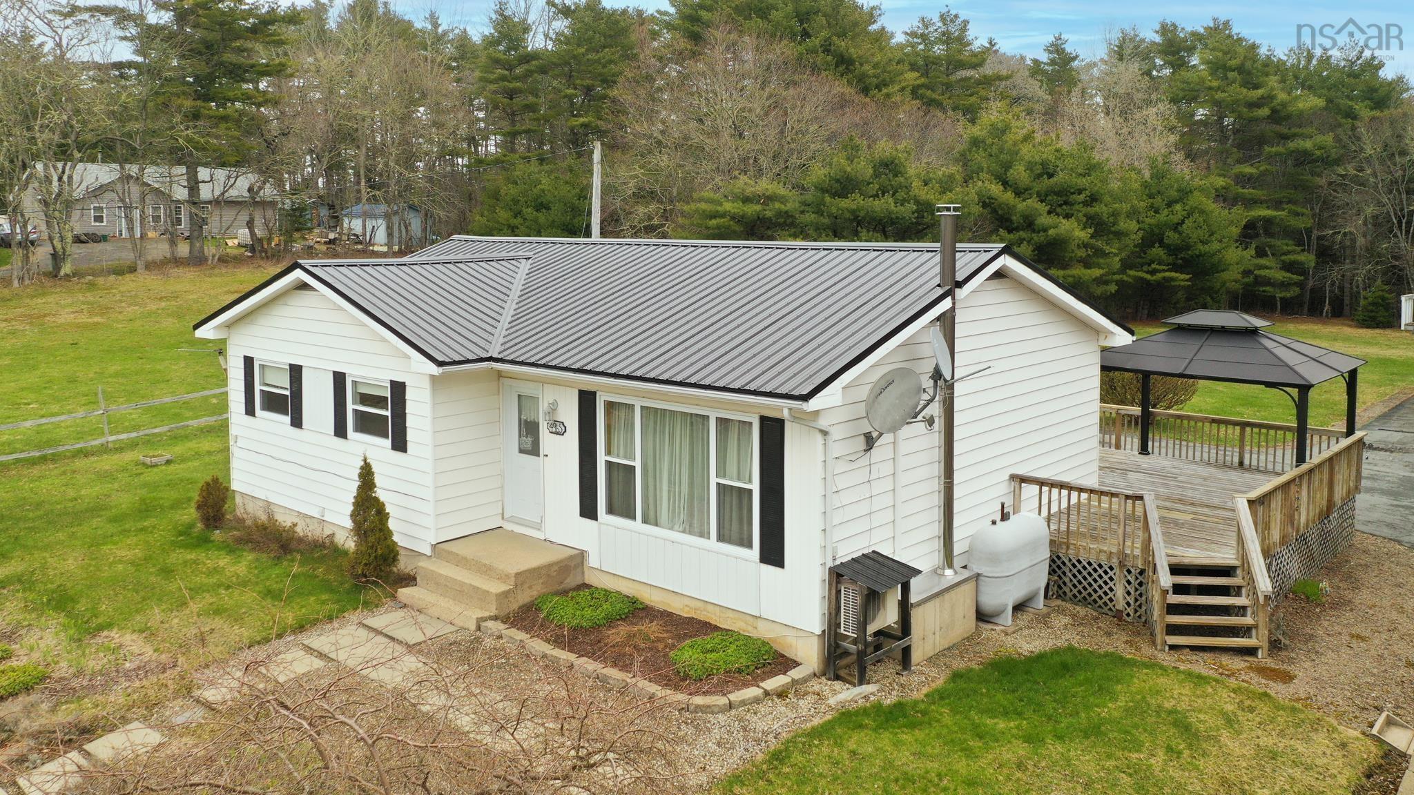 Exterior view of a white house with a gray metal roof, a deck, and a black gazebo.