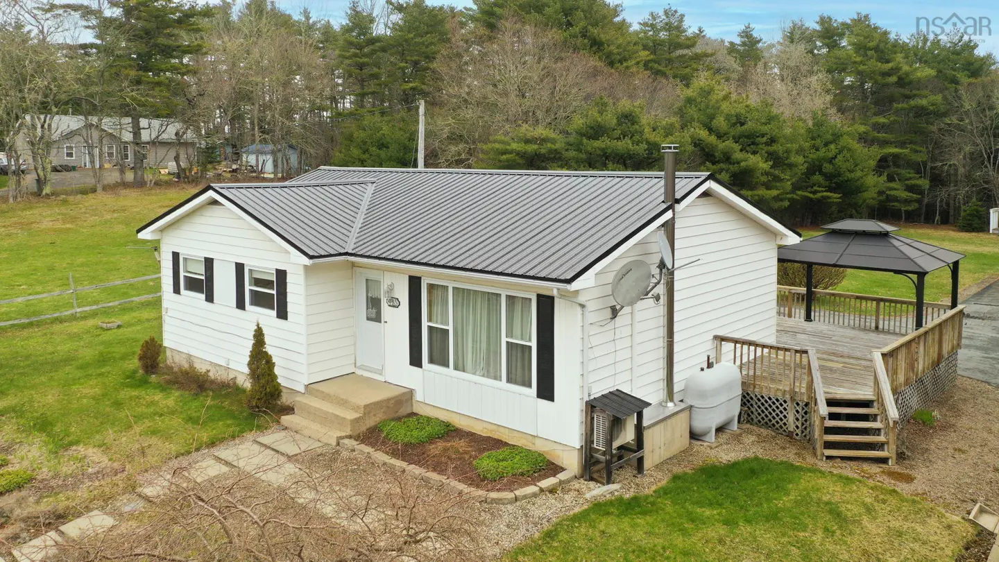Exterior view of a white house with a gray metal roof, a deck, and a black gazebo.