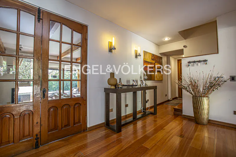 Interior view of a home's entryway with wood floors, a console table, and a glass-paneled wood door.