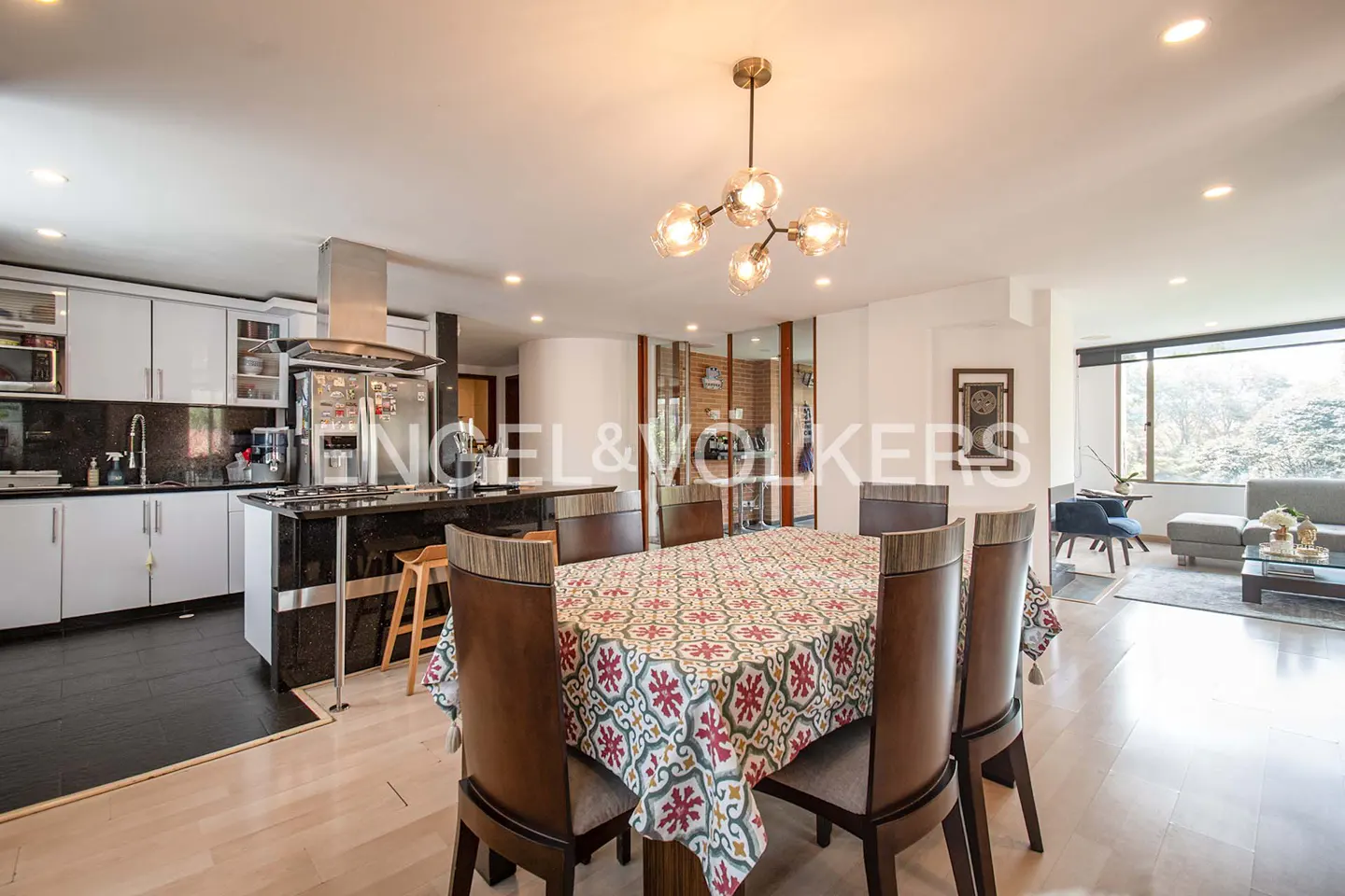 Open-concept kitchen and dining area with white cabinets, black countertops, and a dining table with a patterned tablecloth.