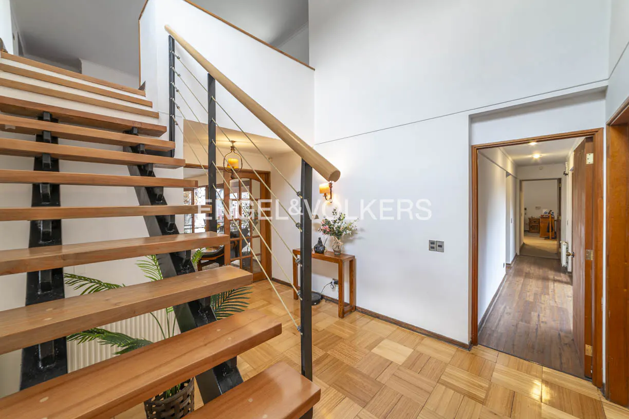 Interior view of a home featuring a wooden staircase with black metal supports, a wooden handrail, and a parquet floor.