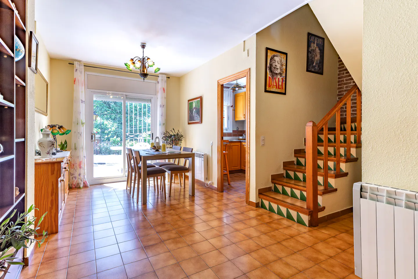Bright dining room with tile floor, table, chairs, and sliding glass door to the outside. Stairs lead to the upper level.